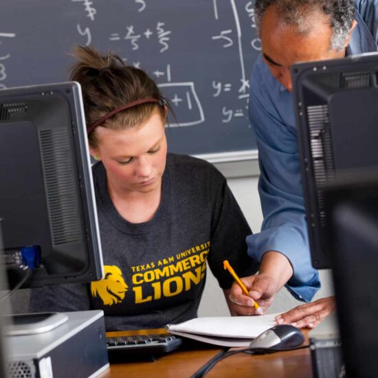A professor helping a female student with an assignment.