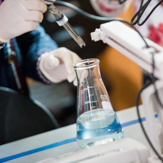 Someone pouring chemical products into a vial.