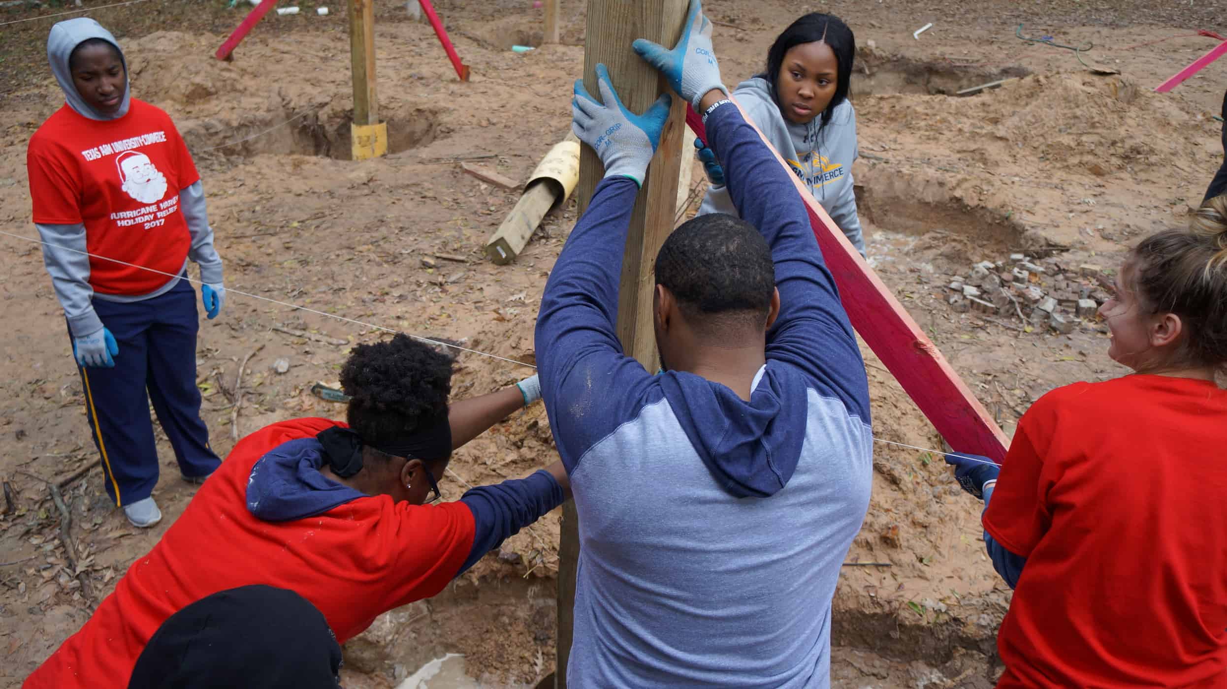 three individuals holding up a pole