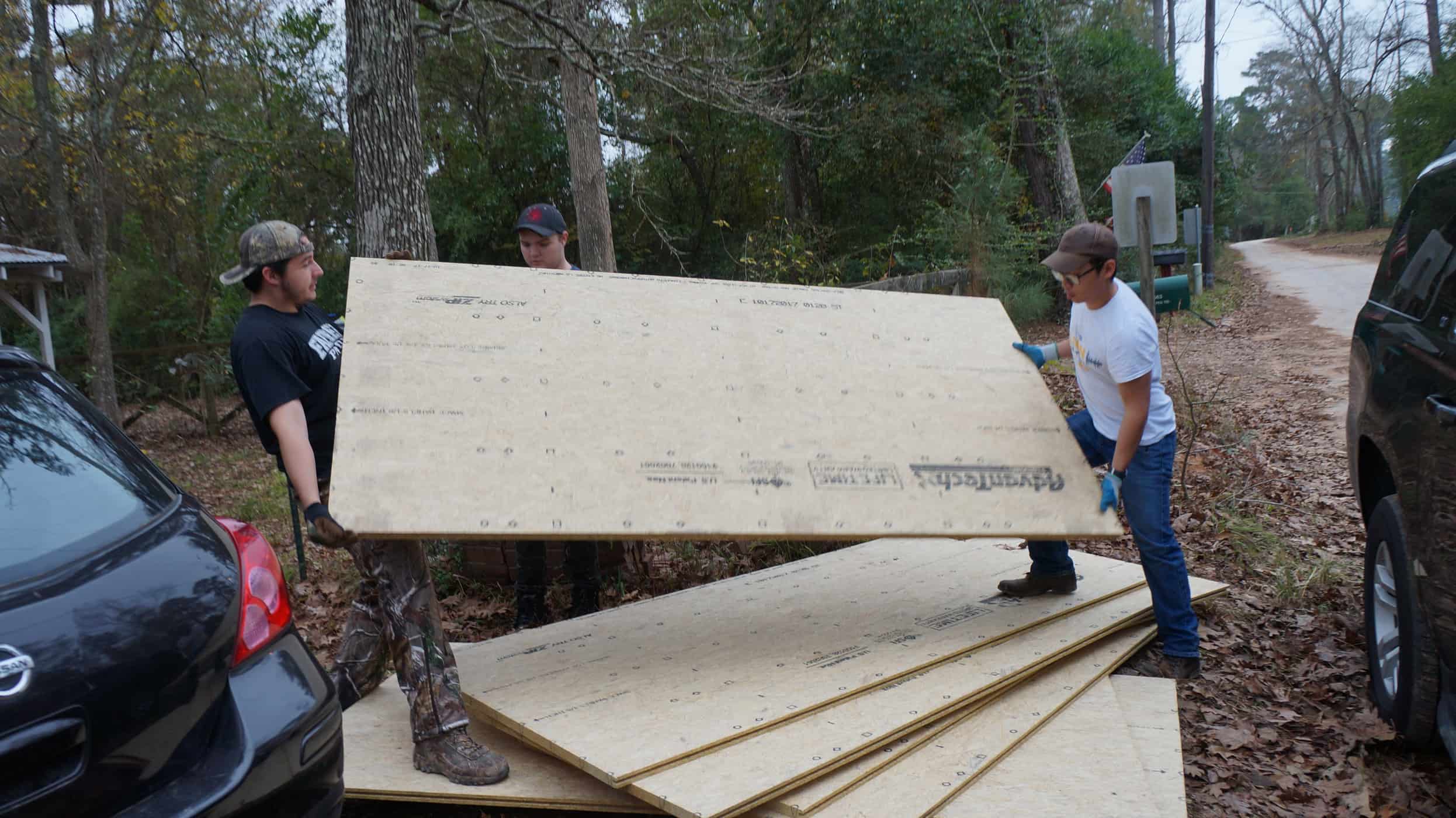 Two individuals carrying drywood