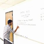 an individual writing out an equation on a white board.