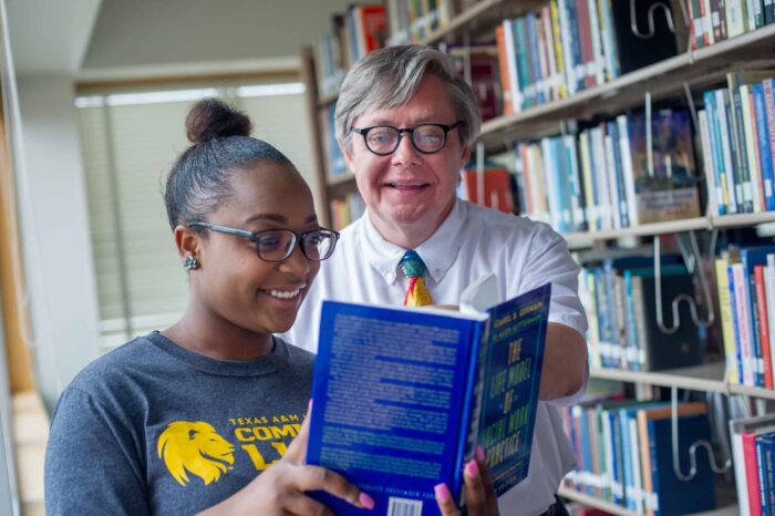 Two people in library looking at a book