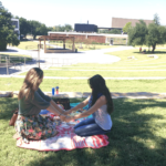 two females holding hands and praying outside.
