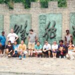 A group of students standing by an exotic wall