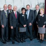 A group of individuals wearing business attire smiling at the camera man.