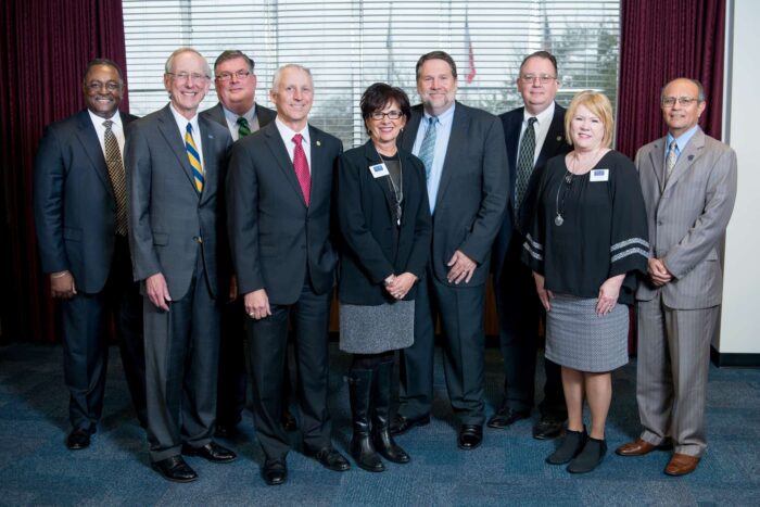 A group of individuals wearing business attire smiling at the camera man.