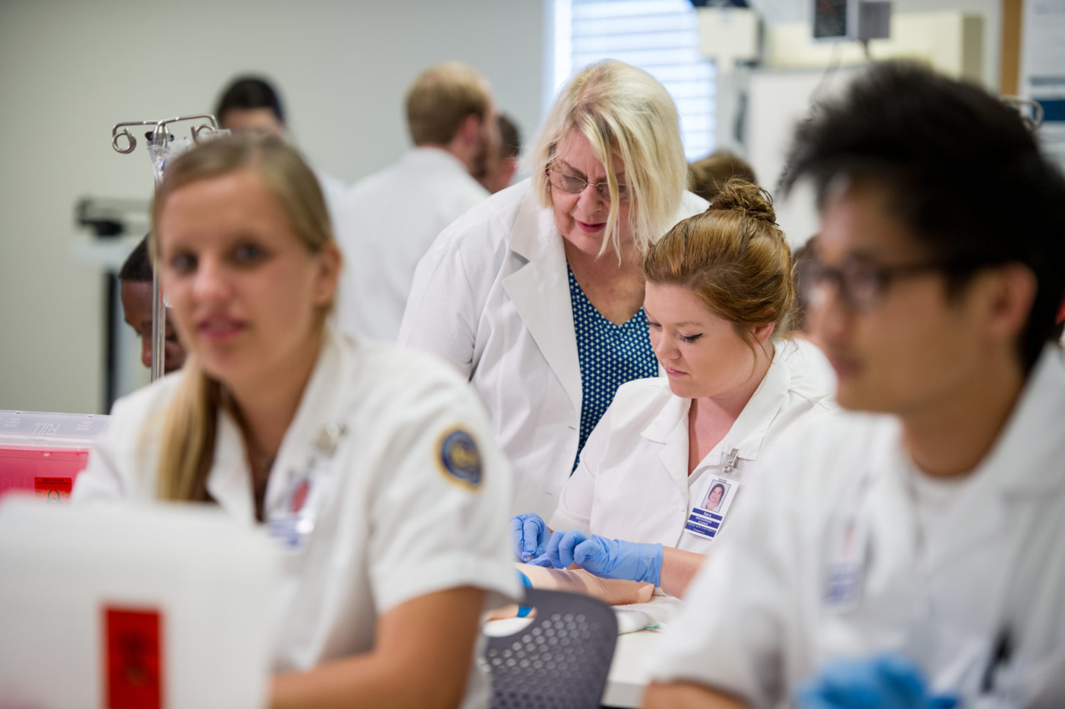 Female nursing instructor helping female nursing students