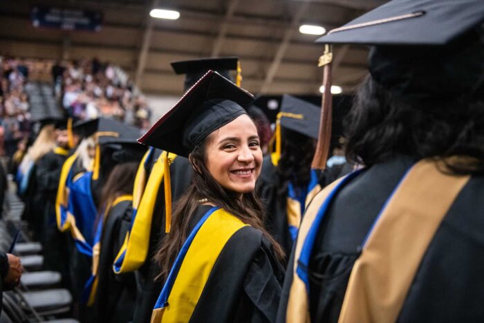 Graduate student smiling at the camera during graduation.