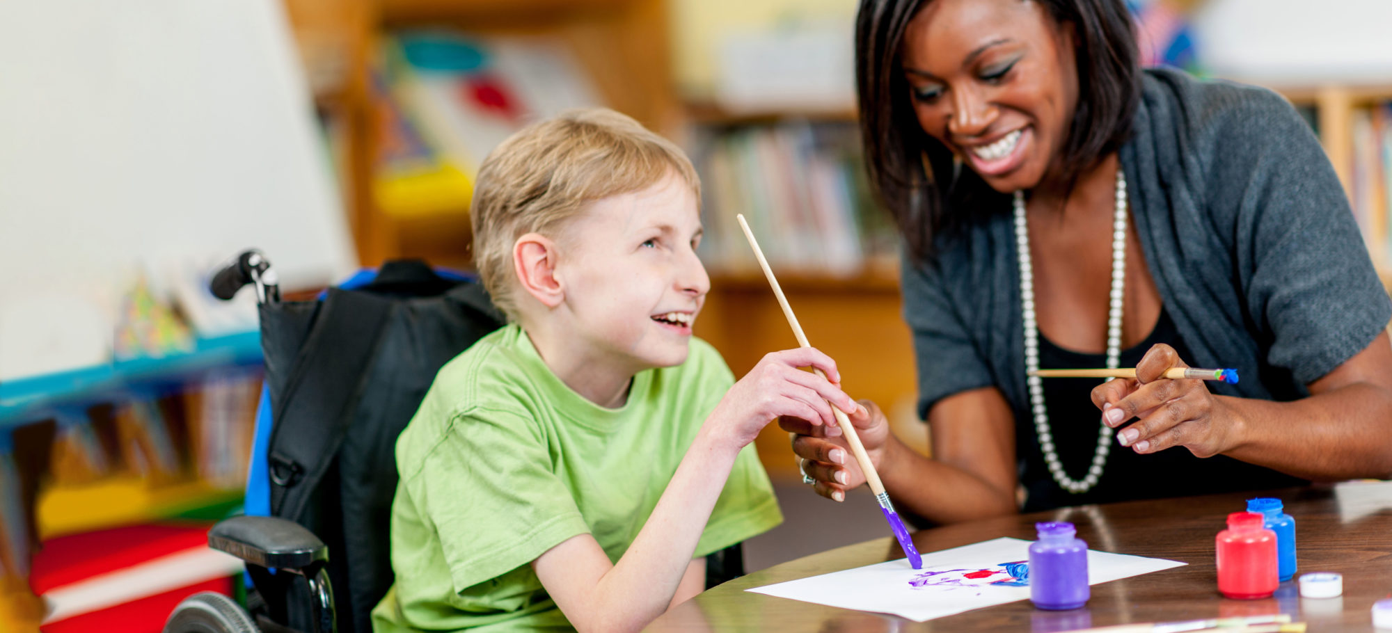 Special Education teacher interacting with student in a classroom.