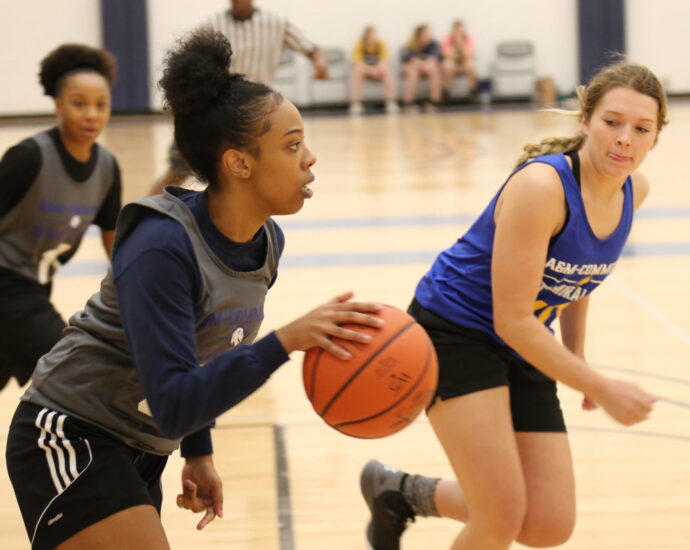 Three females students playing basketball.