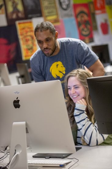 Teacher looking over the shoulder of a student using a computer.