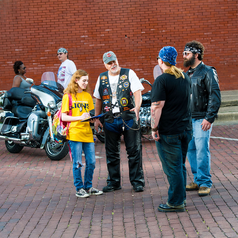 East Texas A&M student interviewing three bikers.