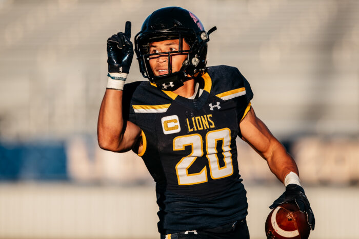 Dominqiue Ramsey in Lion football gear, holding a football.