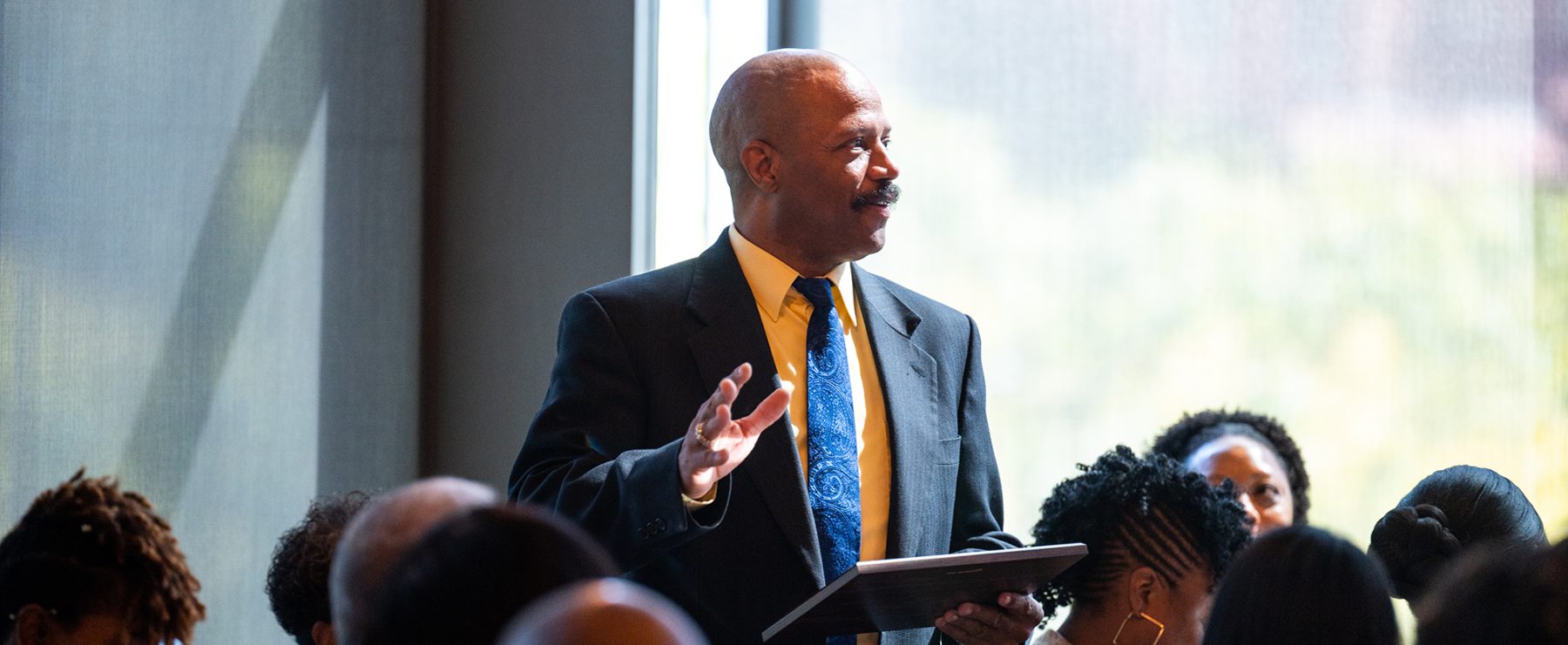 Professor in a suit in tie teaching students.