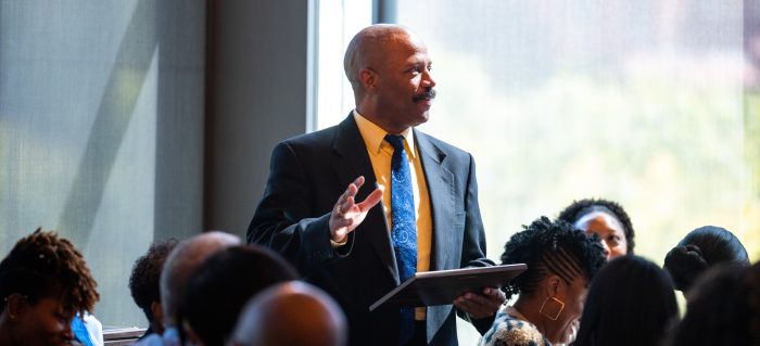 Professor in a suit in tie teaching students.