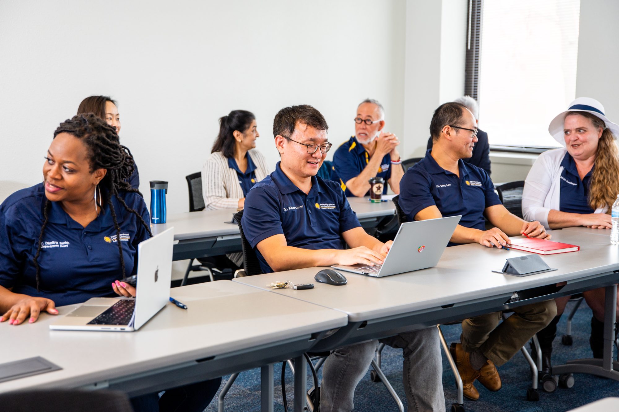 A group of East Texas A&M faculty and staff engage in a collaborative meeting, working on laptops and discussing ideas.