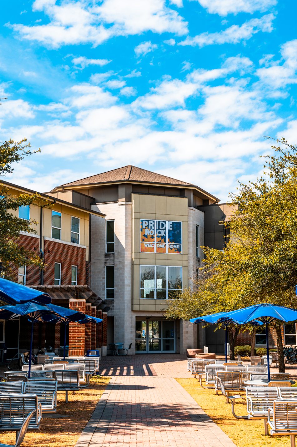 The Pride Rock residence hall at East Texas A&M University greets students with a welcoming sign, outdoor seating and shaded gathering spaces.
