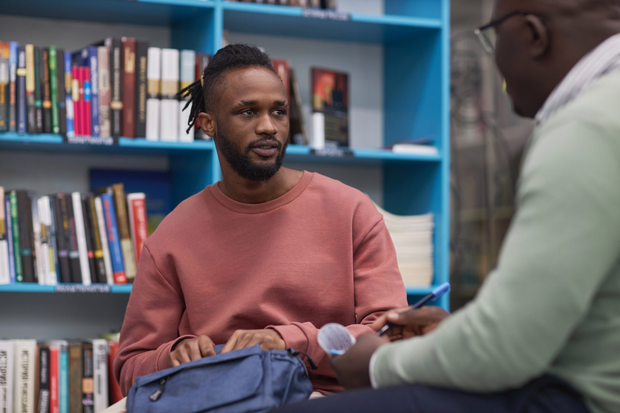 A male looking at a male mentor asking him questions.