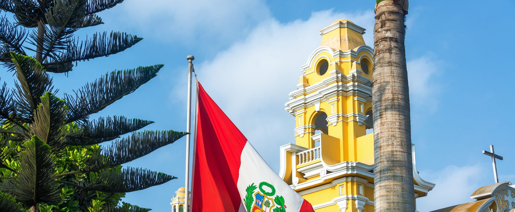 Peruvian flag flying in front of a yellow building