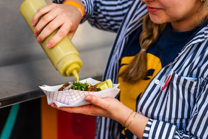 Closeup of student squeezing tube of sauce on to plate of food