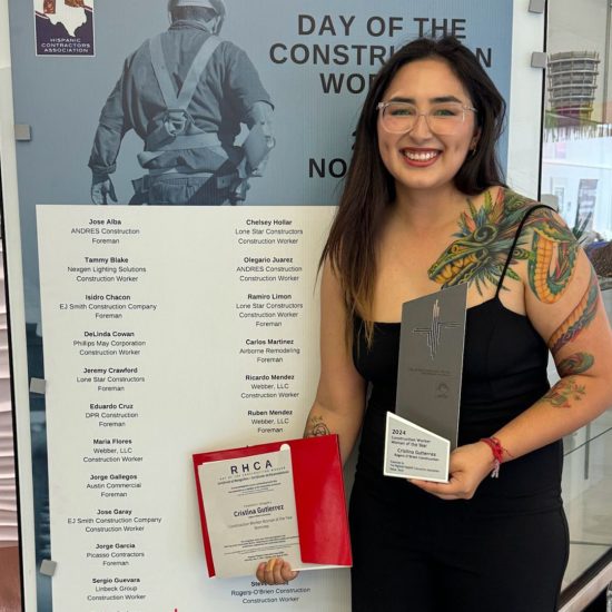 A woman holds an award and certificate in front of a photo backdrop.