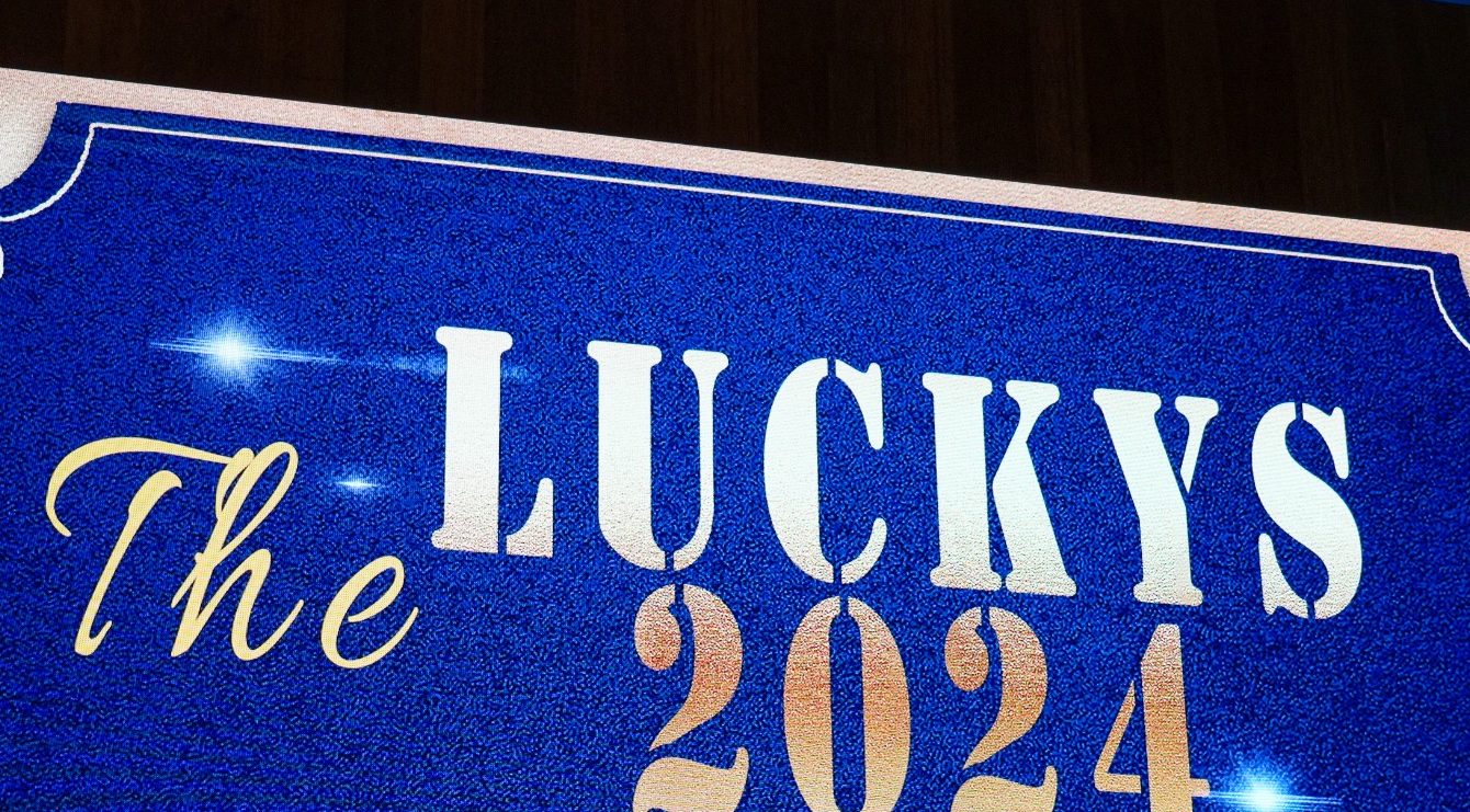 Sign welcoming guests to The Luckys 2024. Sign reads "The Luckys 2024" with blue background and white and gold lettering.