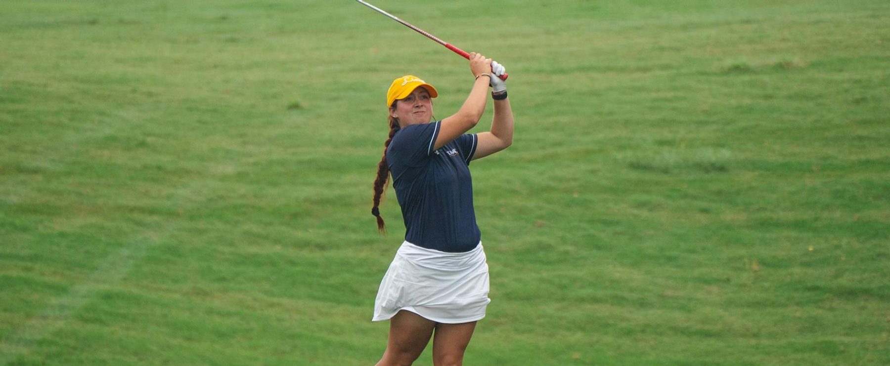 Golfer swings a club on a golf course.