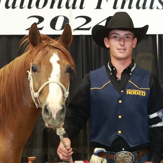A person in western attire poses for a photo next to a horse.