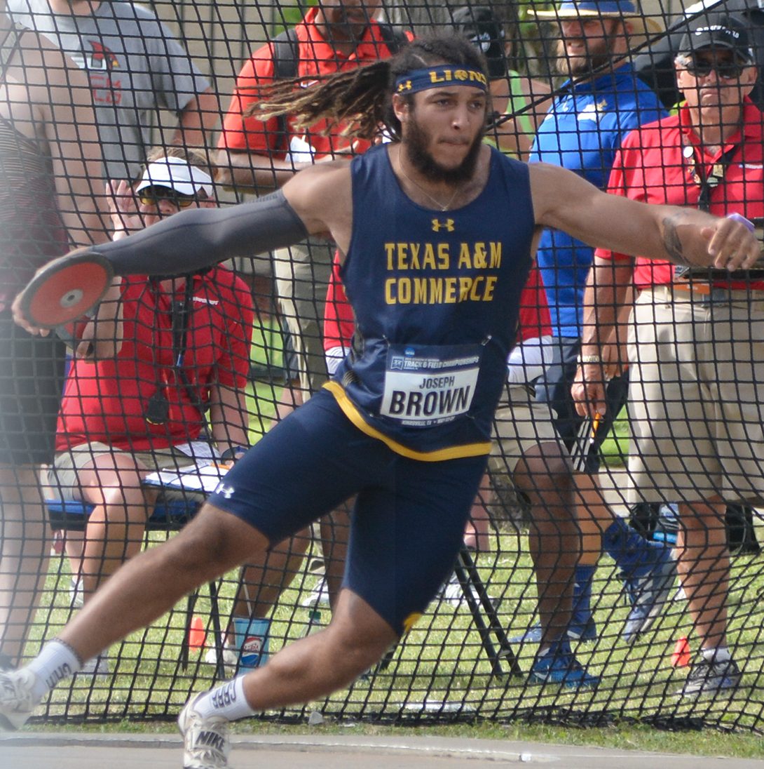 Athlete throws the discus with spectators watching in the background.