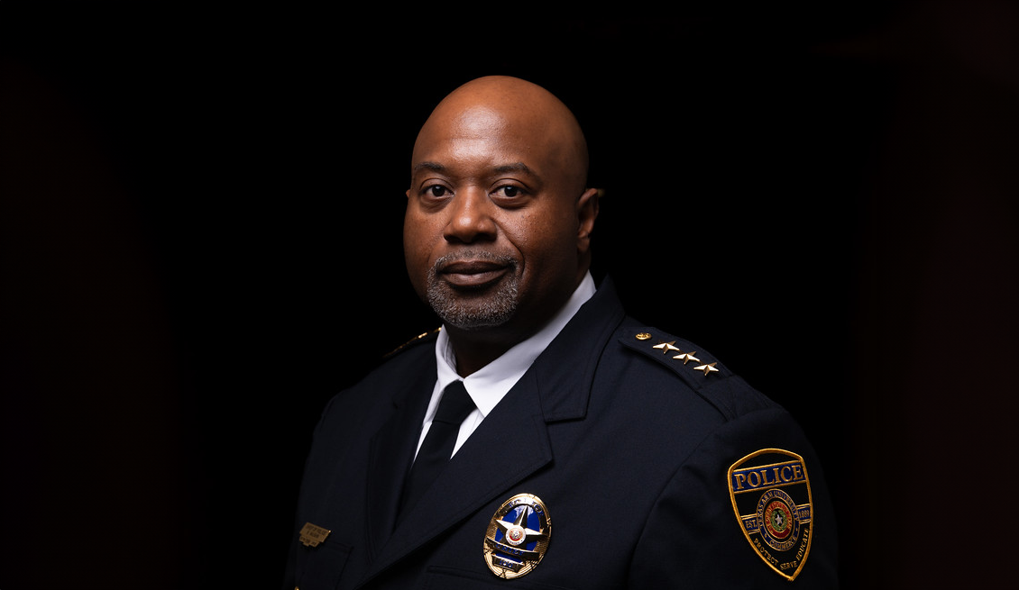 Against a black background, Chief Vaughn smiles slightly, wearing his formal police uniform and badge.