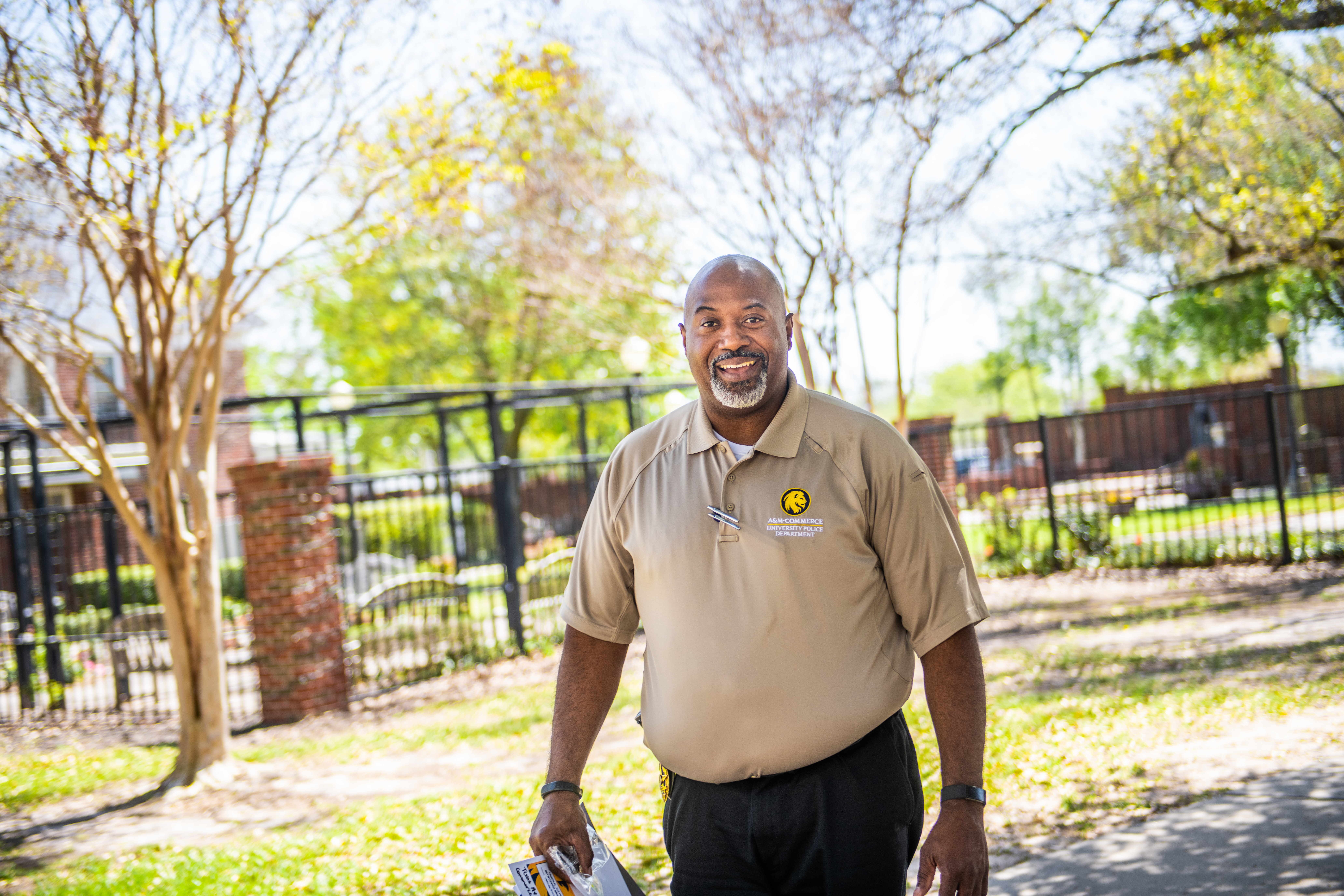 Chief Bryan Vaughn, dressed in a khaki-colored polo and dark slacks, walking past the Lyday Heritage Gardens on the campus of Texas A&M-Commerce.