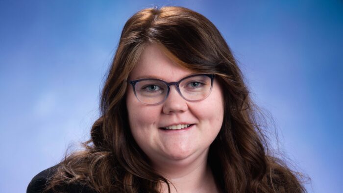 Headshot photograph of woman wearing glasses and smiling.