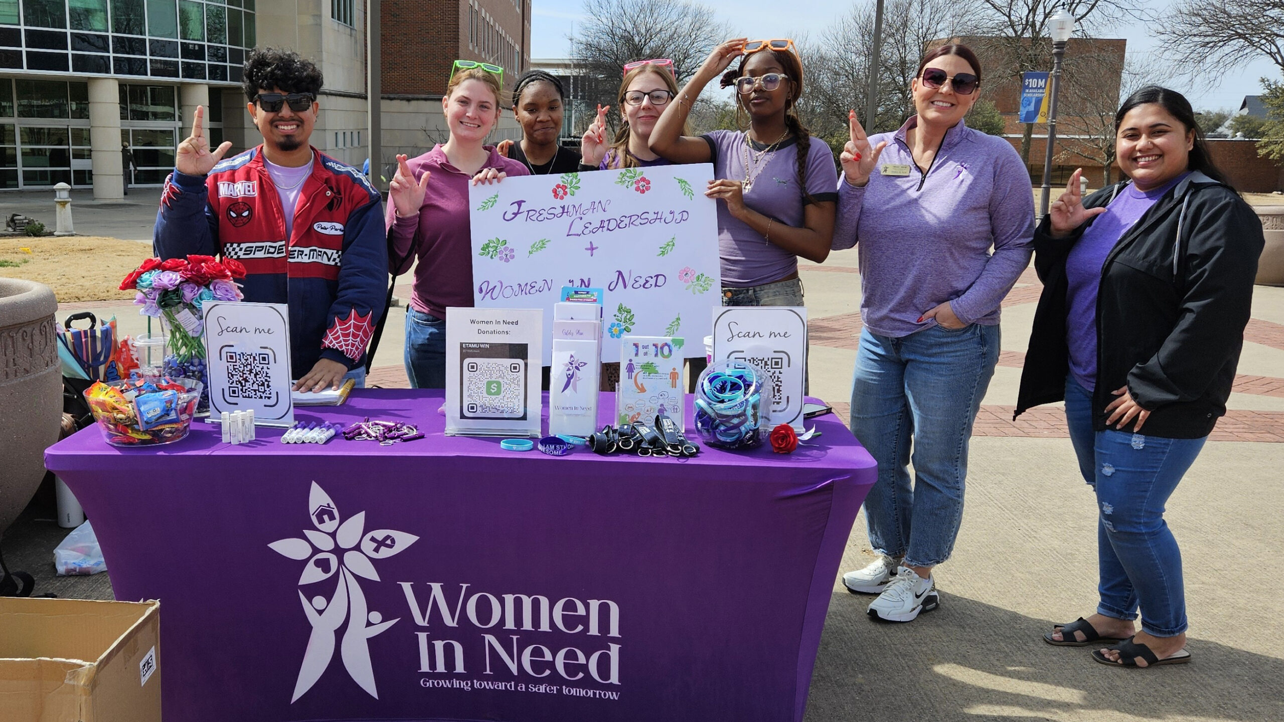 A group of people pose for a photo while standing near an informational booth outdoors.