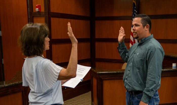 A man in a long-sleeved shirt holding his right arm up, and a woman holding her right arm up.