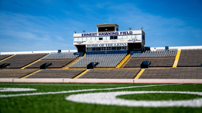 A football stadium photographed from midfield on a sunny day.