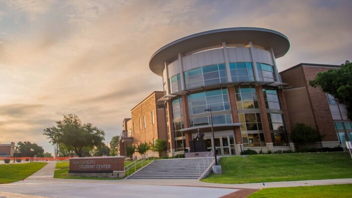 Outdoors picture of the Sam Rayburn Student Center, with the sun and clouds in the background.