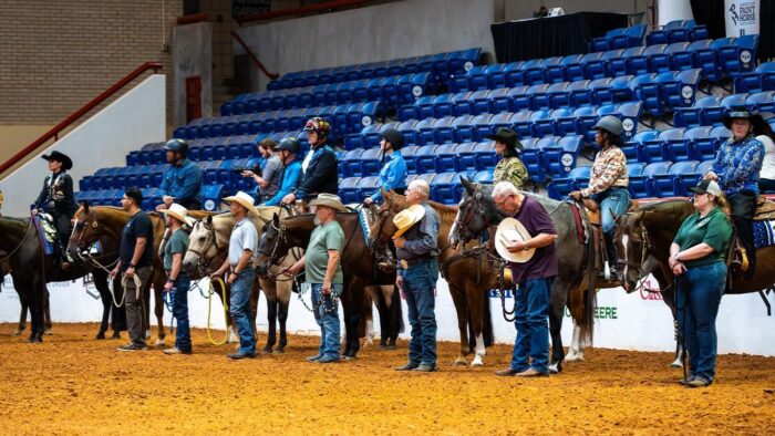 A line of riders on horses before a horse show competition.