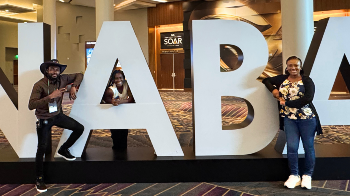 People in a convention center posing near large letters spelling NABA.