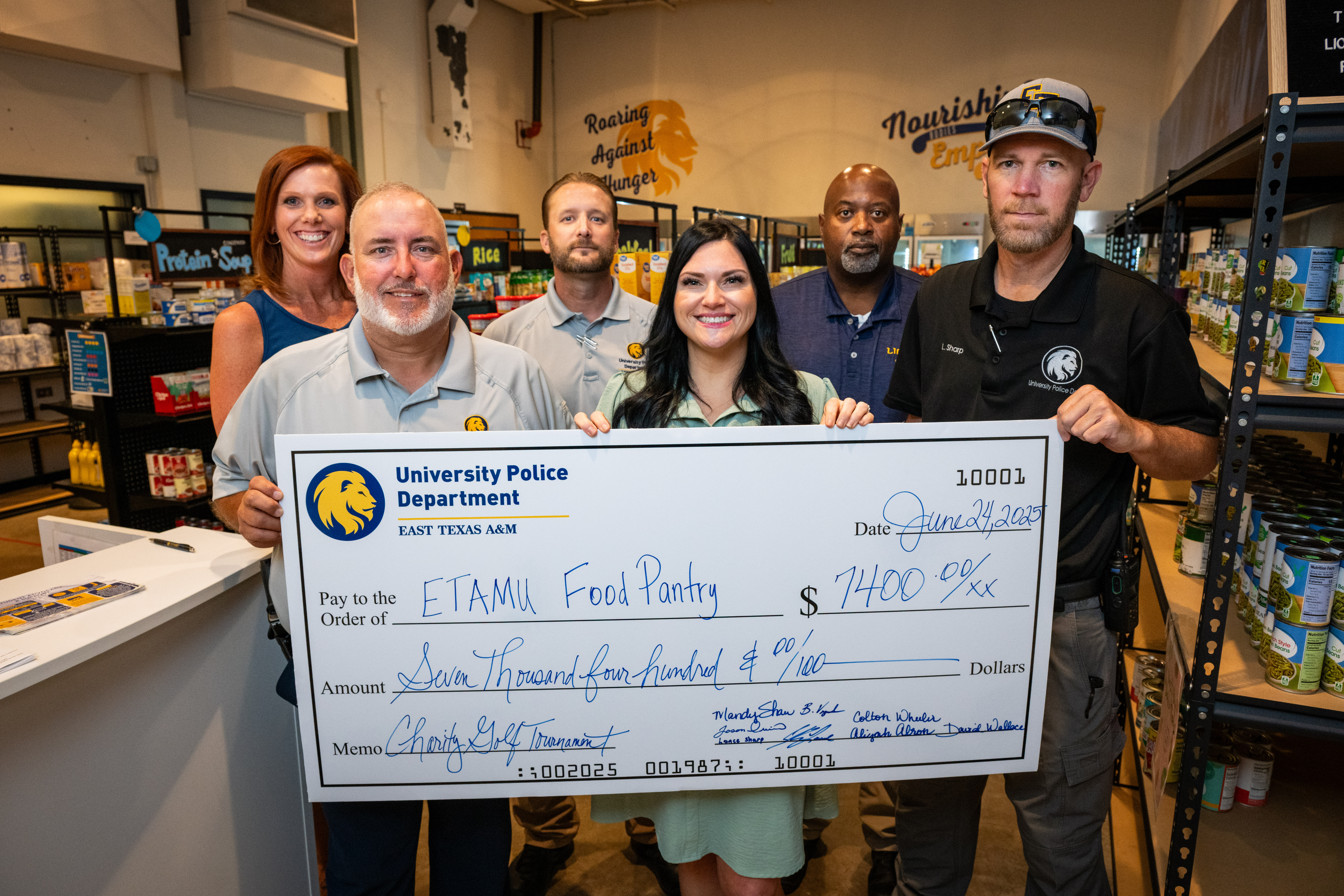 Four men and two women stand with a large depiction of a check to the food pantry for $7400.