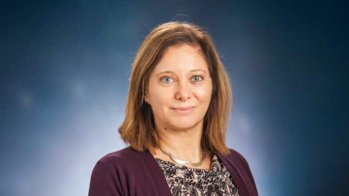 A headshot photo of a person on a blue background.
