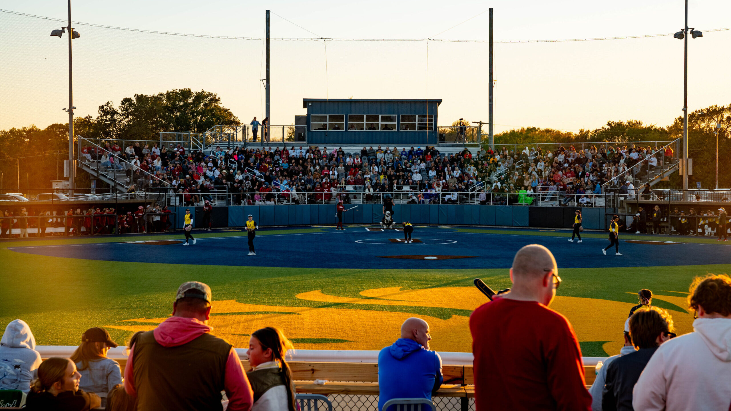 A softball stadium filled with fans watching a game.