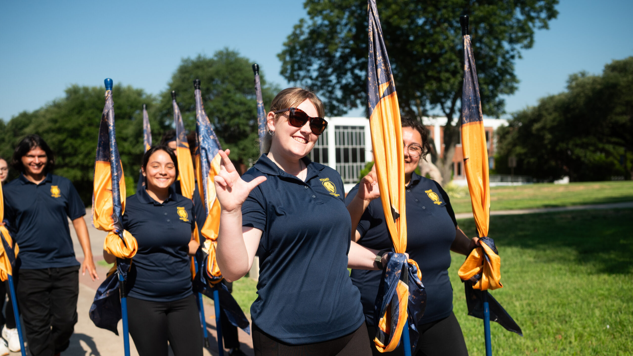 Decorative photo. Students hold blue and gold school flags and walk together.