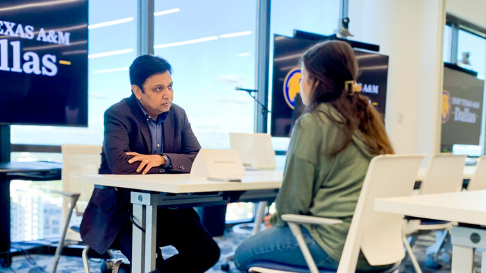 A man sitting at a desk across from a young woman.