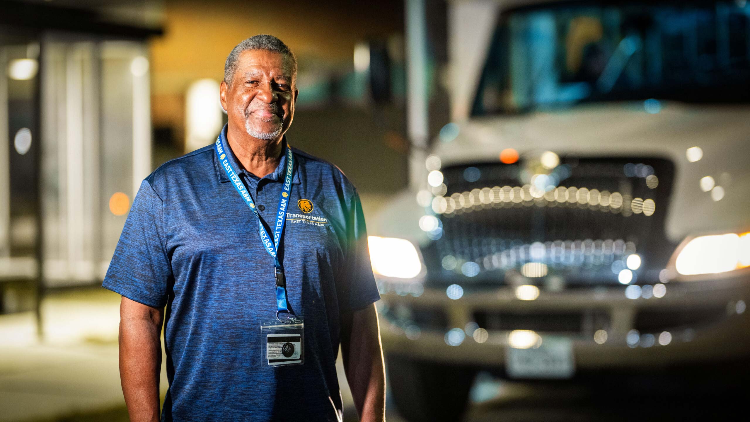 Man standing outside in front of a bus, smiling.
