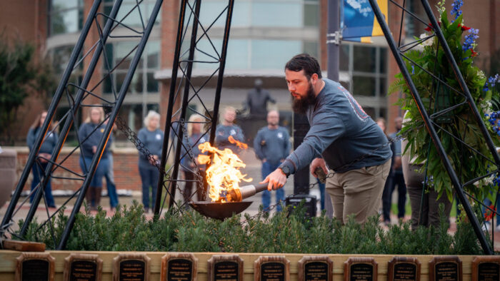 A person using a torch to light a ceremonial flame.