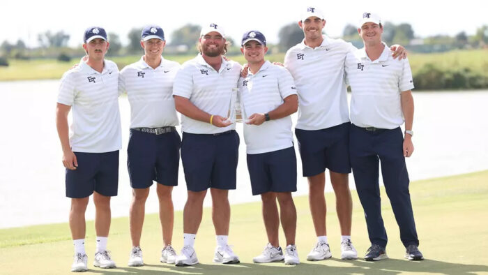 A group of people standing side by side posing with a trophy.
