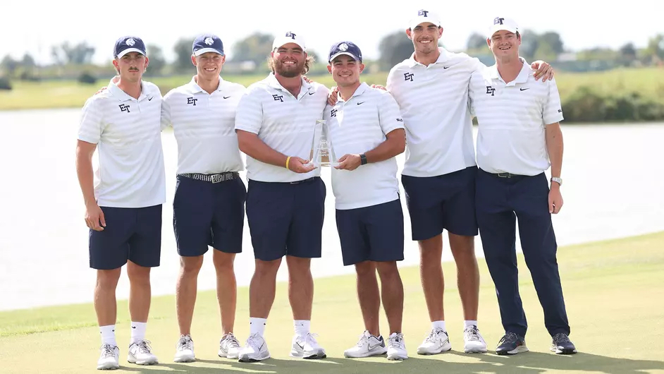 A group of people standing side by side posing with a trophy.