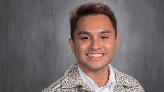 Adrian Anderson smiling in his headshot with a gray backdrop.