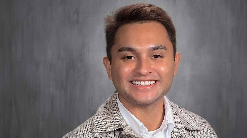 Adrian Anderson smiling in his headshot with a gray backdrop.