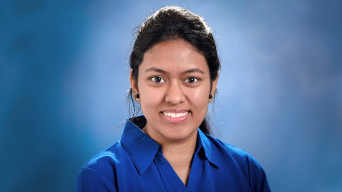 Tejaswini Atluri smiling in her headshot with a light blue backdrop.